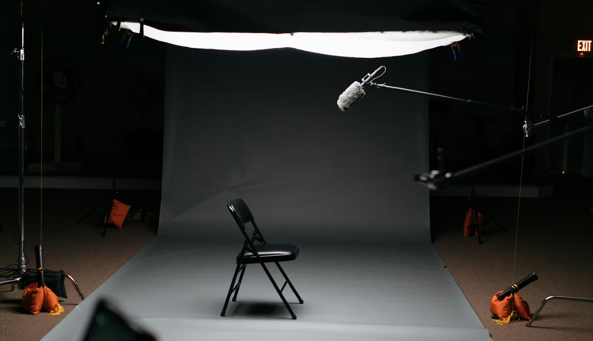Lit interview setup with grey backdrop, boom microphone and diffusion overhead